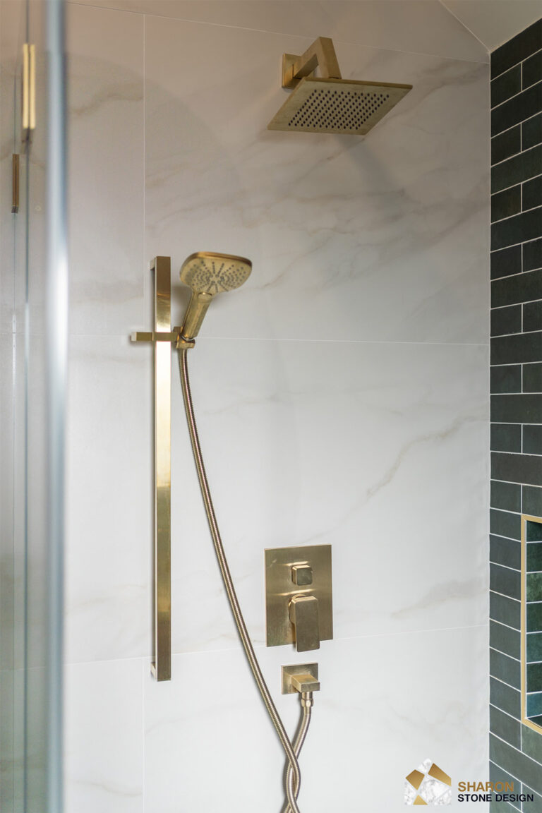 Palo Alto bathroom remodel shower wall with a ceiling-height brushed brass rain arm, a handheld shower on a tall brass slide bar, and stacked thermostatic controls mounted on white porcelain with soft veins beside the green tile return.