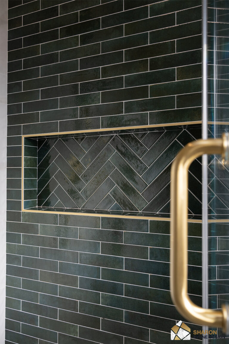 Palo Alto bathroom remodel shampoo niche detail, its interior laid in herringbone green tile and outlined in slim brushed brass Schluter profile against the running-bond green subway surround.