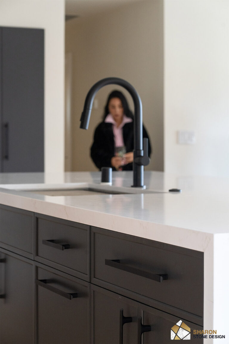 Redwood City home remodel island photographed from the working side, the matte black faucet and stainless sink sharp against charcoal shaker drawers with black bar pulls.