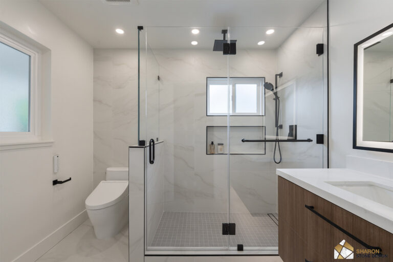 Redwood City home remodel primary bathroom with a walk-in shower under a ceiling-mounted black rain head, a black grab bar and handheld, a shampoo niche and window trimmed in black Schluter profile, a gray mosaic shower floor, and a walnut vanity opposite.