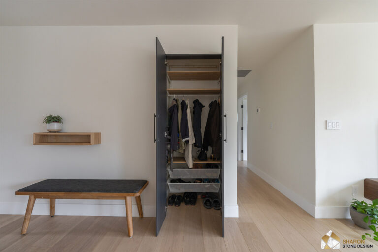 Redwood City home remodel entry closet standing open to reveal oak shelving and pull-out mesh shoe baskets, with the oak bench and floating shelf alongside.