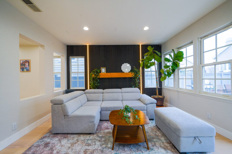 Redwood City home remodel living room with a black slat feature wall lit by vertical LED reveals and a solid oak mantel shelf.