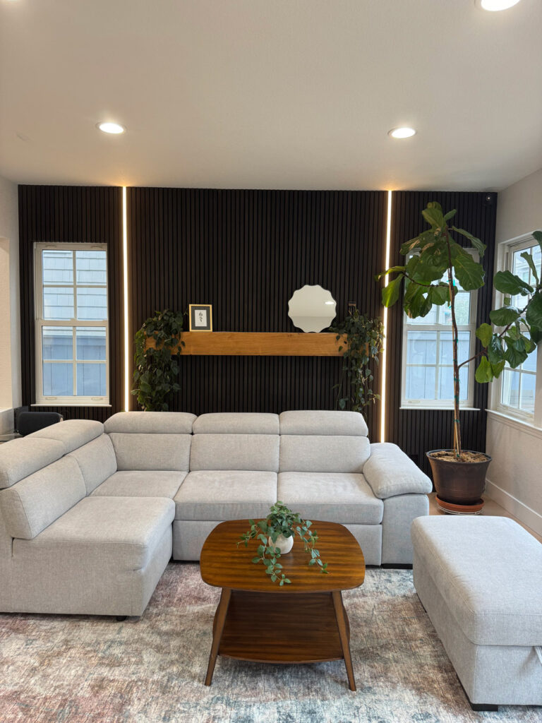 Redwood City home remodel living room from the side, showing the LED-lit black slat wall running to the window corner.
