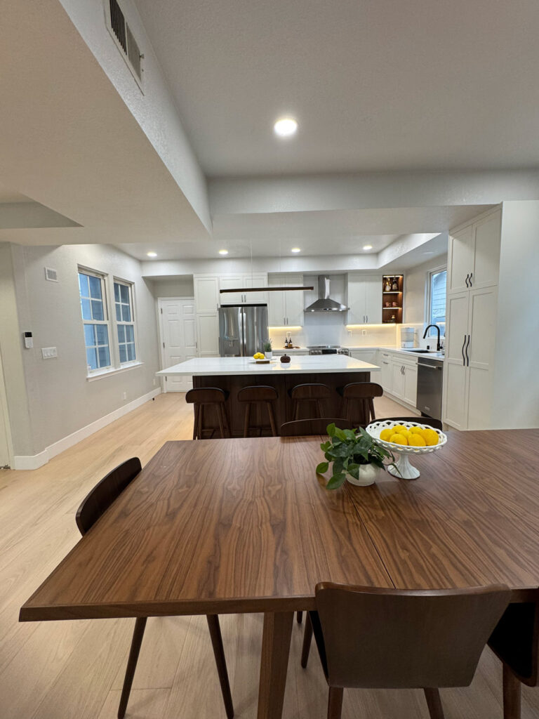 Redwood City home remodel looking toward the kitchen, with the quartz island and stainless appliances beyond the dining area.
