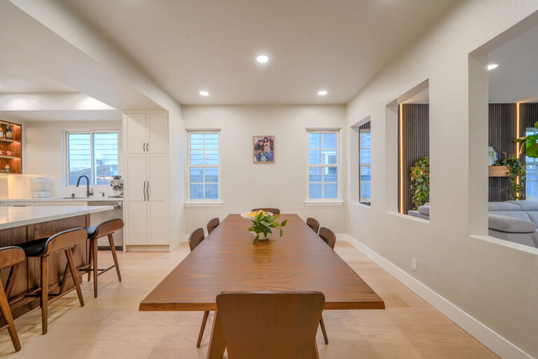 Redwood City home remodel dining room between two windows, with interior openings framing the black slat wall in the adjoining living room.