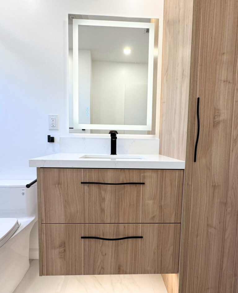 San Jose bathroom remodel vanity elevation, a walnut floating cabinet with two drawers and sculpted wavy black pulls beneath a quartz top with integrated upstand, a black faucet and a backlit LED mirror.