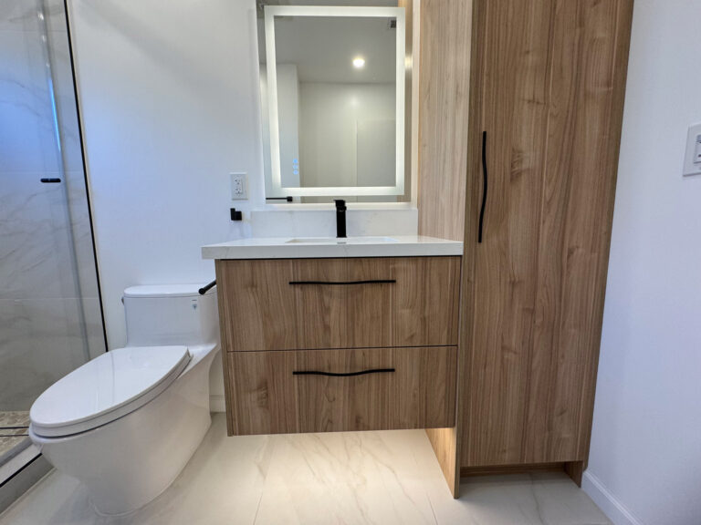 San Jose bathroom remodel vanity seen at an angle, the walnut cabinet appearing to float above marble-look floor tile beside a matching full-height linen tower, with the shower glass at left.