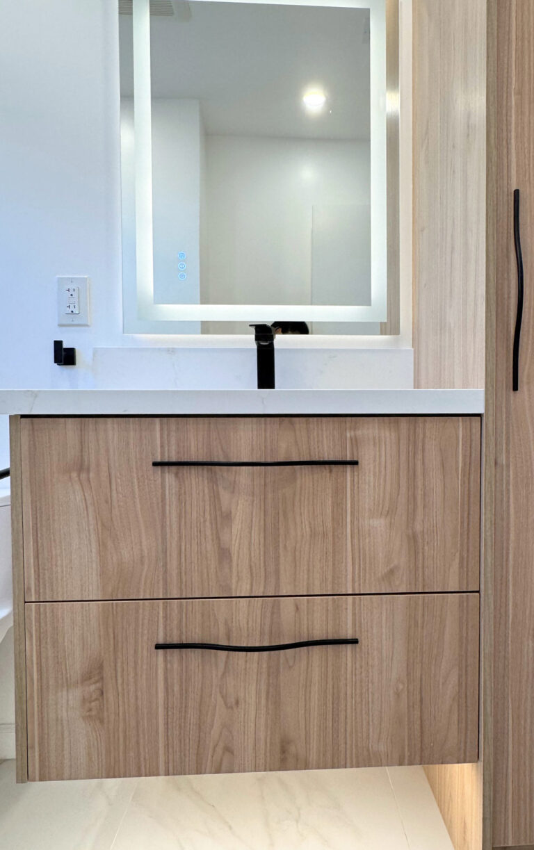 San Jose bathroom remodel vanity photographed straight on, the walnut cabinet with two sculpted black pulls floating above marble-look floor tile beneath a quartz top and touch-control LED mirror.