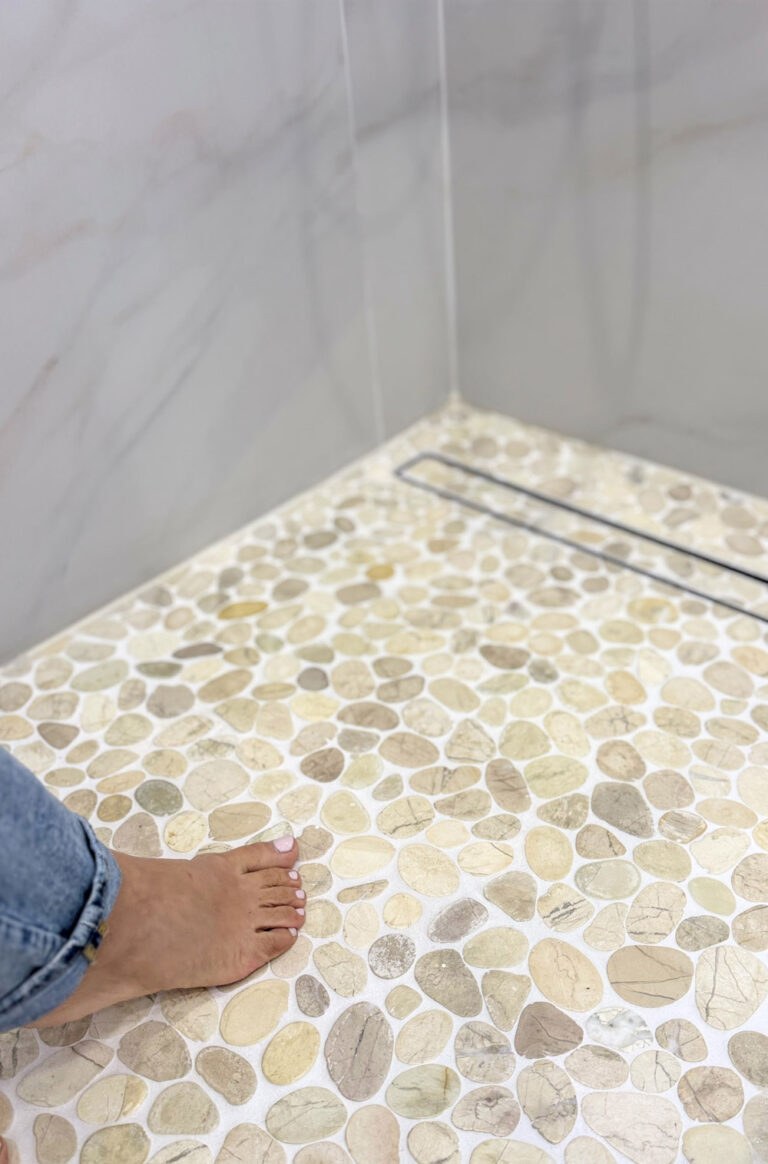 San Jose bathroom remodel pebble mosaic shower floor, showing the flush black linear drain running along the Calacatta-look wall.