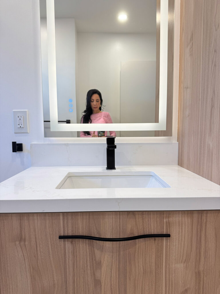 San Jose bathroom remodel vanity with the quartz counter and upstand, a matte black square faucet and a rectangular undermount basin below the backlit mirror.